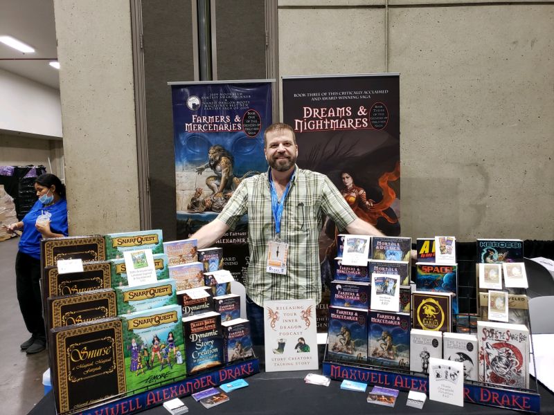 Maxwell Alexander Drake at his convention booth with the books he has written