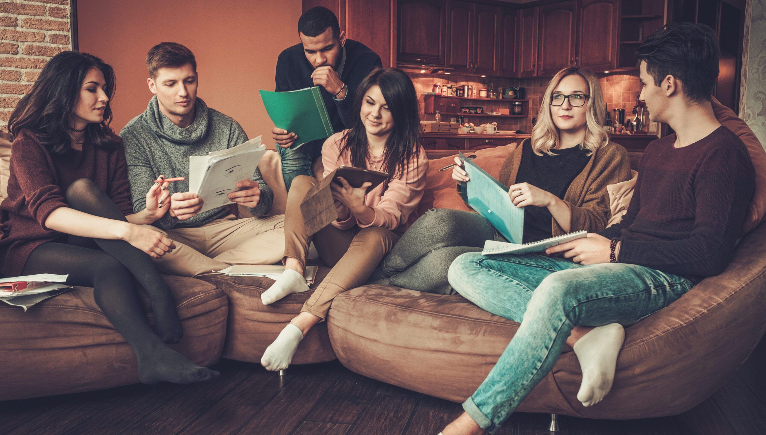 Group of multi ethnic young students preparing for exams in home interior.